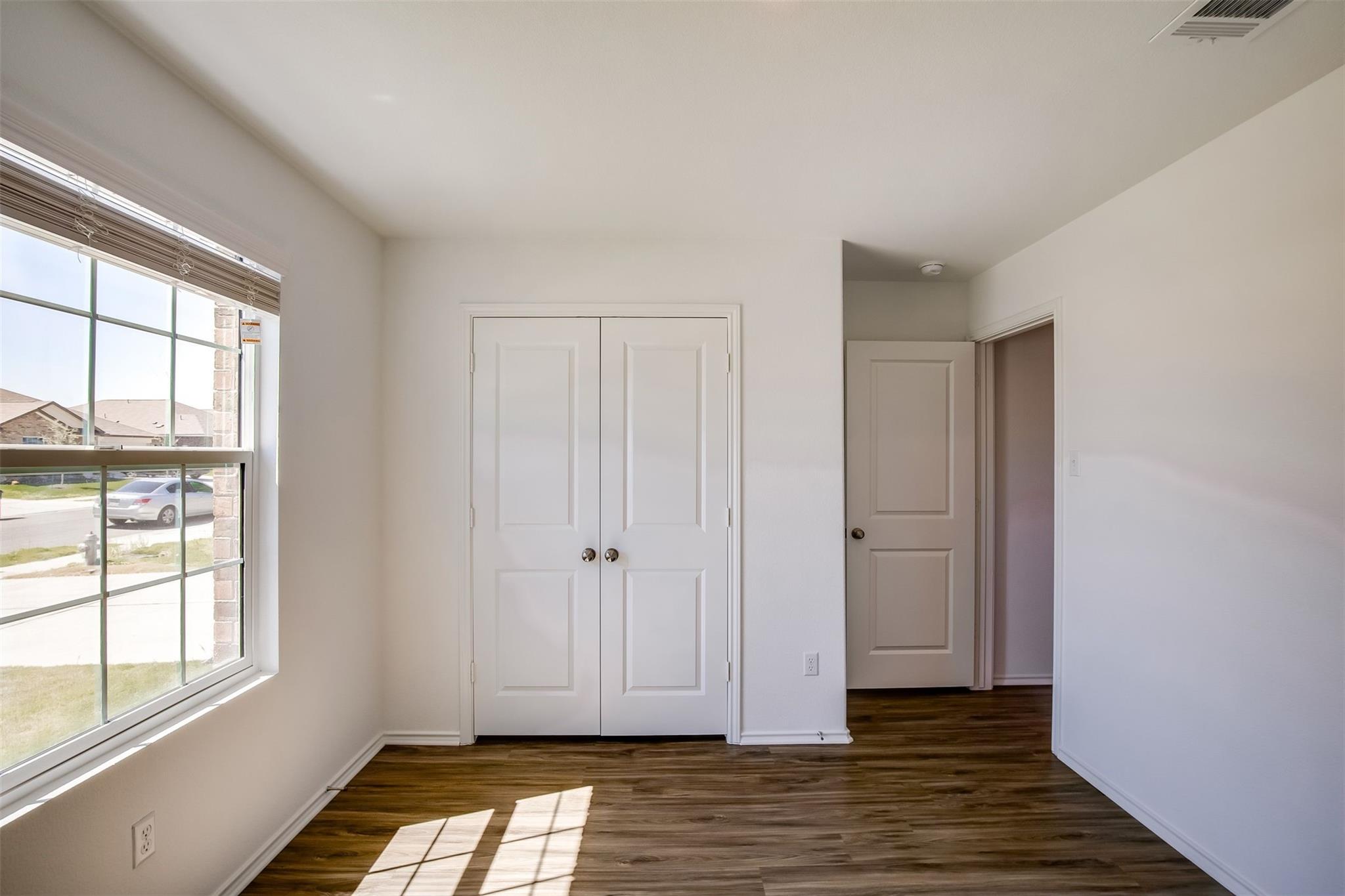 614 Milliner Loop Hutto, TX 78634 - Photo 10 of 25 A quiet secondary bedroom features durable wood-look flooring and a window overlooking the community.
