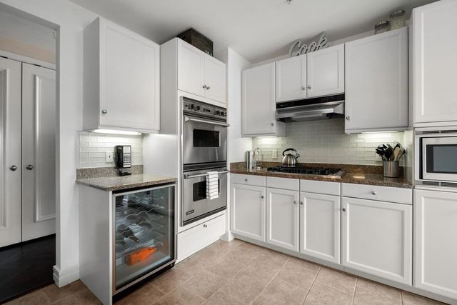 a kitchen with stainless steel appliances granite countertop a stove and white cabinets