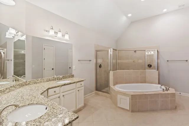 a bathroom with a granite countertop tub double vanity sink and mirror