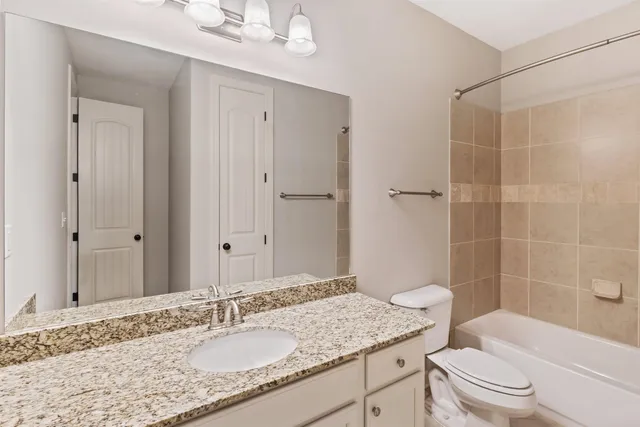 a bathroom with a granite countertop sink a toilet a mirror and shower