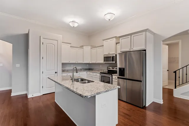 a kitchen that has a refrigerator a stove top oven a counter space and wooden floor