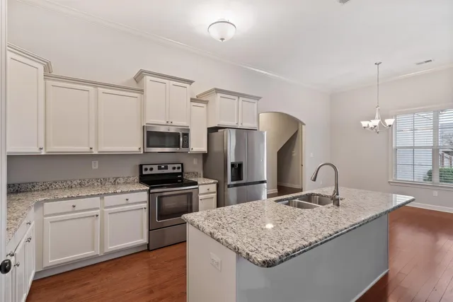 a kitchen with granite countertop a sink stainless steel appliances and white cabinets