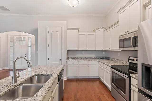 a kitchen with granite countertop a sink stainless steel appliances and white cabinets