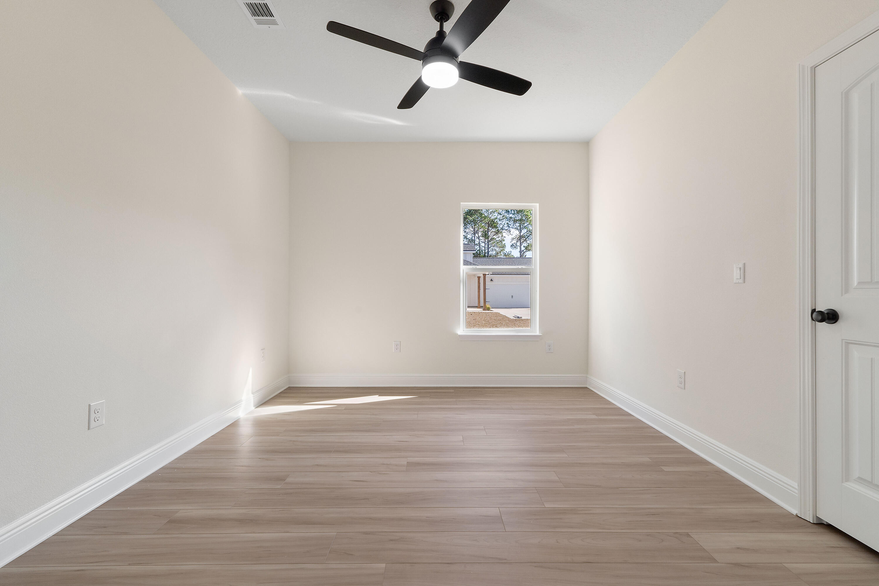8370 Sevilla Street Navarre, FL 32566 - Photo 7 of 12 an empty room with wooden floor ceiling fan and windows
