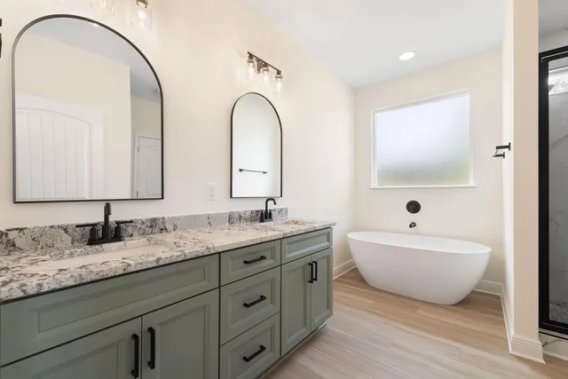 a spacious bathroom with a double vanity sink mirror and bathtub