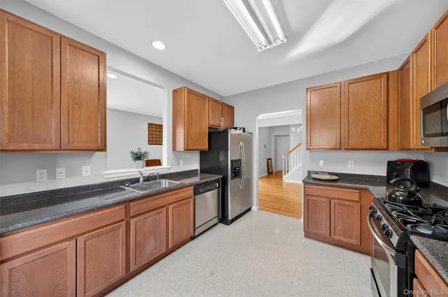 a kitchen with stainless steel appliances granite countertop a stove a sink dishwasher a refrigerator and cabinets with wooden floor