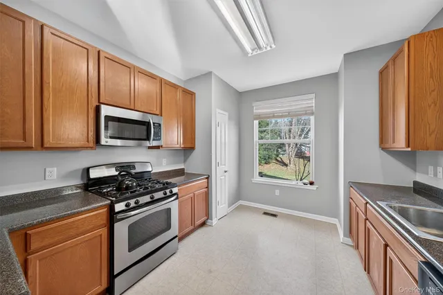 a kitchen with stainless steel appliances granite countertop a stove a sink and a microwave