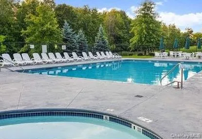 a view of a swimming pool with a bench and trees in the background