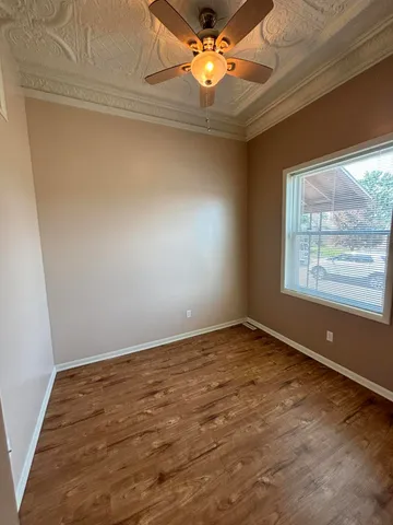 an empty room with a window and chandelier fan