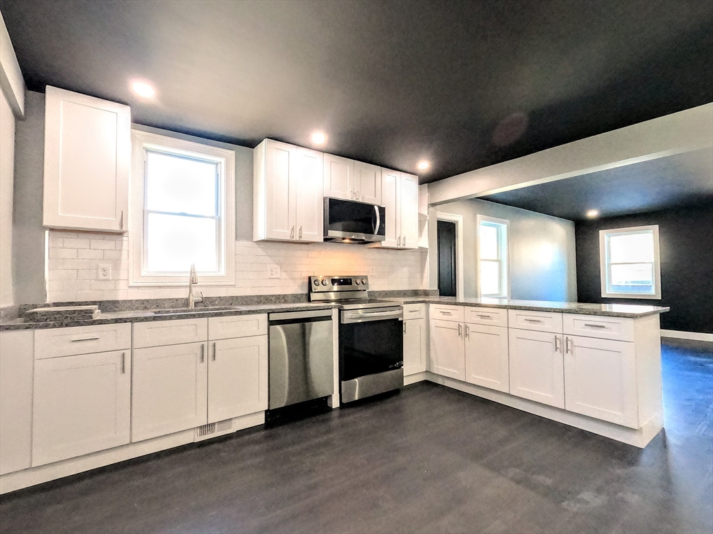 2 Sunnyside Street, Unit 1 Boston, MA 02130 - Photo 17 of 31 a large kitchen with granite countertop a stove and a sink