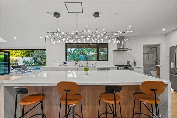 a kitchen with stainless steel appliances a dining table chairs and chandelier