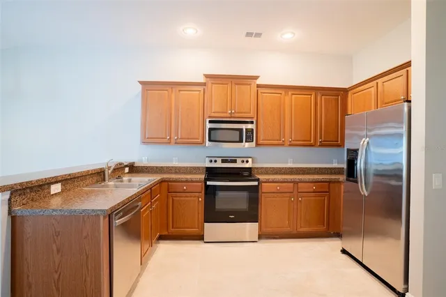 a kitchen with granite countertop a refrigerator stove and microwave