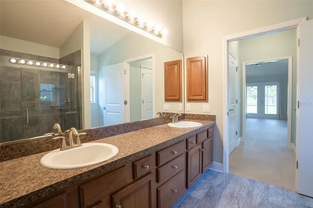 a bathroom with a granite countertop sink a mirror and a shower