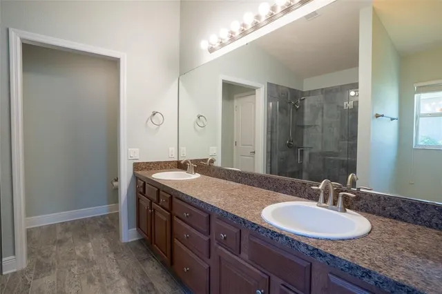 a bathroom with a granite countertop double vanity sink and a mirror