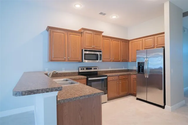 a kitchen with stainless steel appliances granite countertop a refrigerator a stove top oven a sink and dishwasher