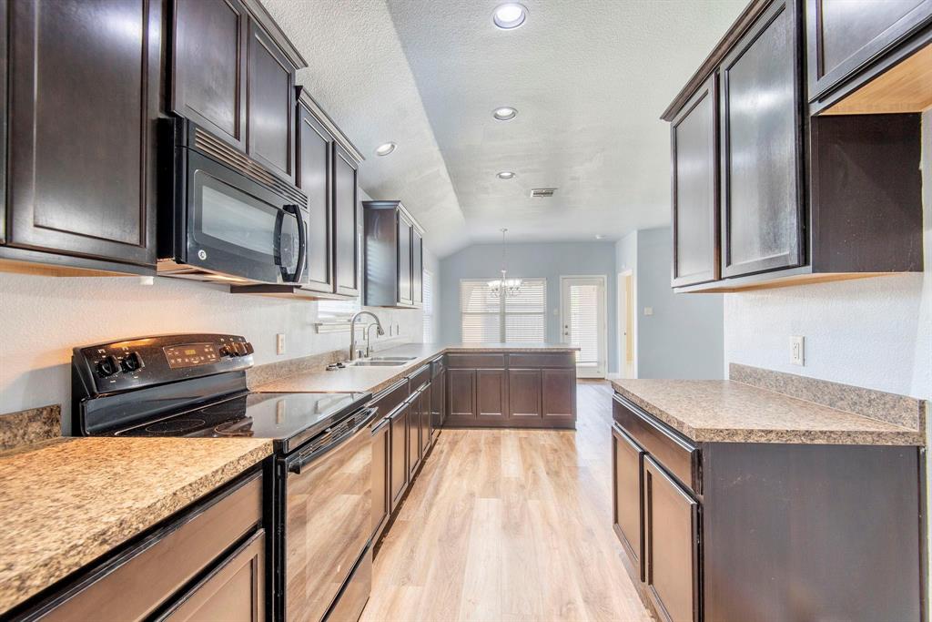 1813 Rodeo Drive Anna, TX 75409 - Photo 3 of 6 Kitchen with black appliances, a chandelier, dark brown cabinetry, light wood-style floors, and a peninsula