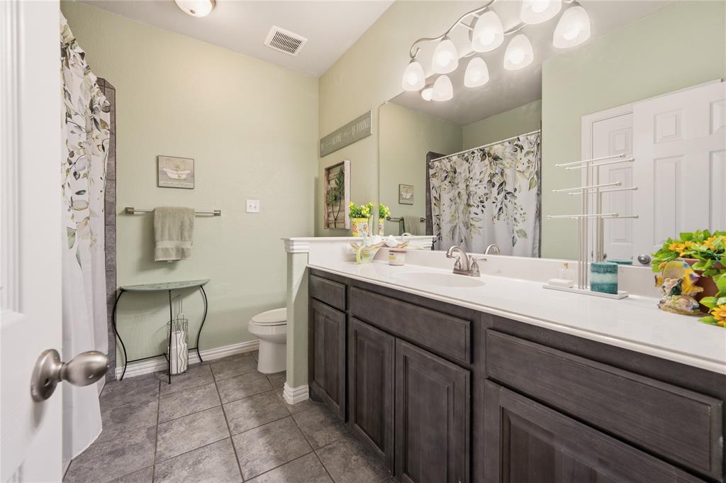 140 Chestnut Road Waxahachie, TX 75165 - Photo 21 of 26 Bathroom featuring a dual vanity with a light countertop, integrated sinks, and dark wood-finish cabinetry