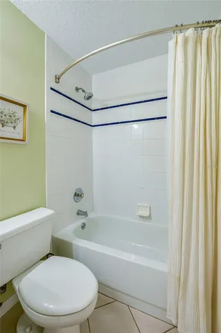 a white toilet and shower sitting next to a white tub
