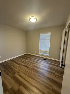an empty room with wooden floor and window