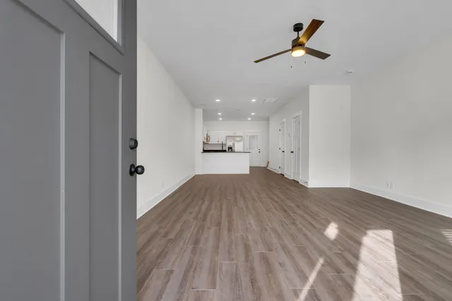 an empty room with wooden floor ceiling fan and window