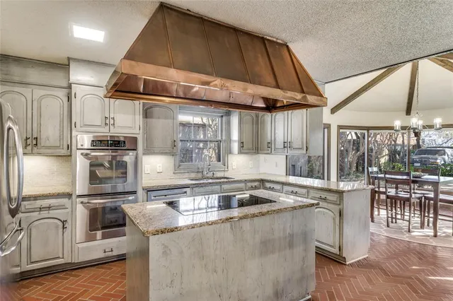 a kitchen with stainless steel appliances granite countertop a sink a stove and a refrigerator