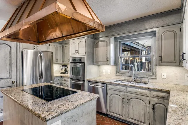 a kitchen with stainless steel appliances granite countertop a sink a stove and cabinets