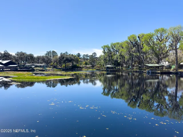 a view of an empty room with wooden floor and a fireplace