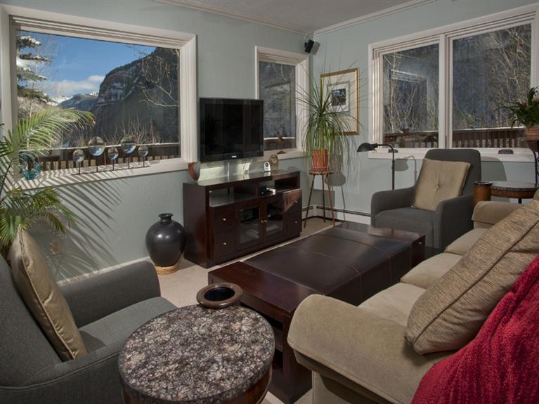 2570 Bald Mountain Road, Unit E Vail, CO 81657 - Photo 4 of 25 a living room with furniture a flat screen tv and a floor to ceiling window