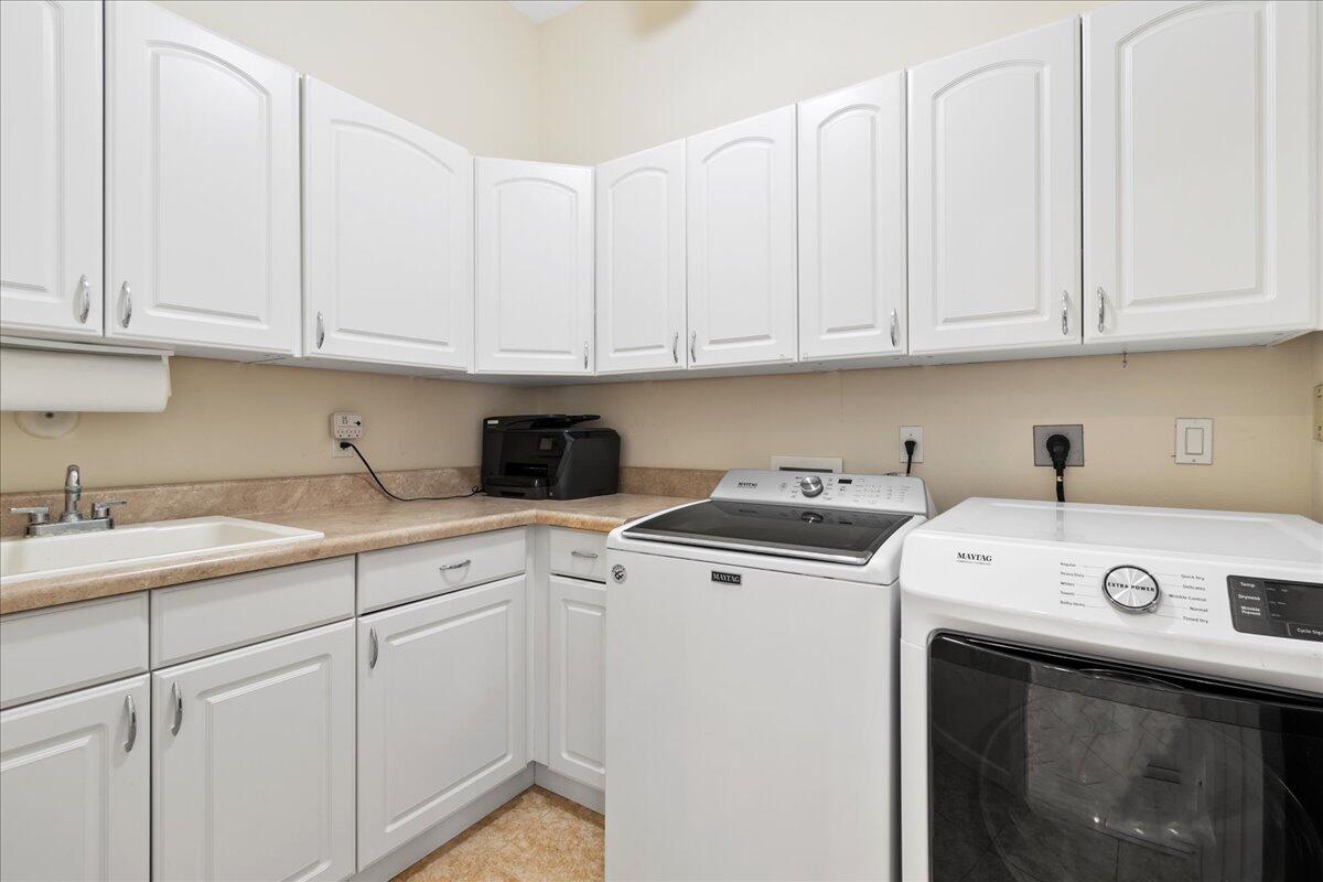 72 Waterway Road Jupiter, FL 33469 - Photo 28 of 57 a utility room with stainless steel appliances granite countertop a sink a washer and cabinets