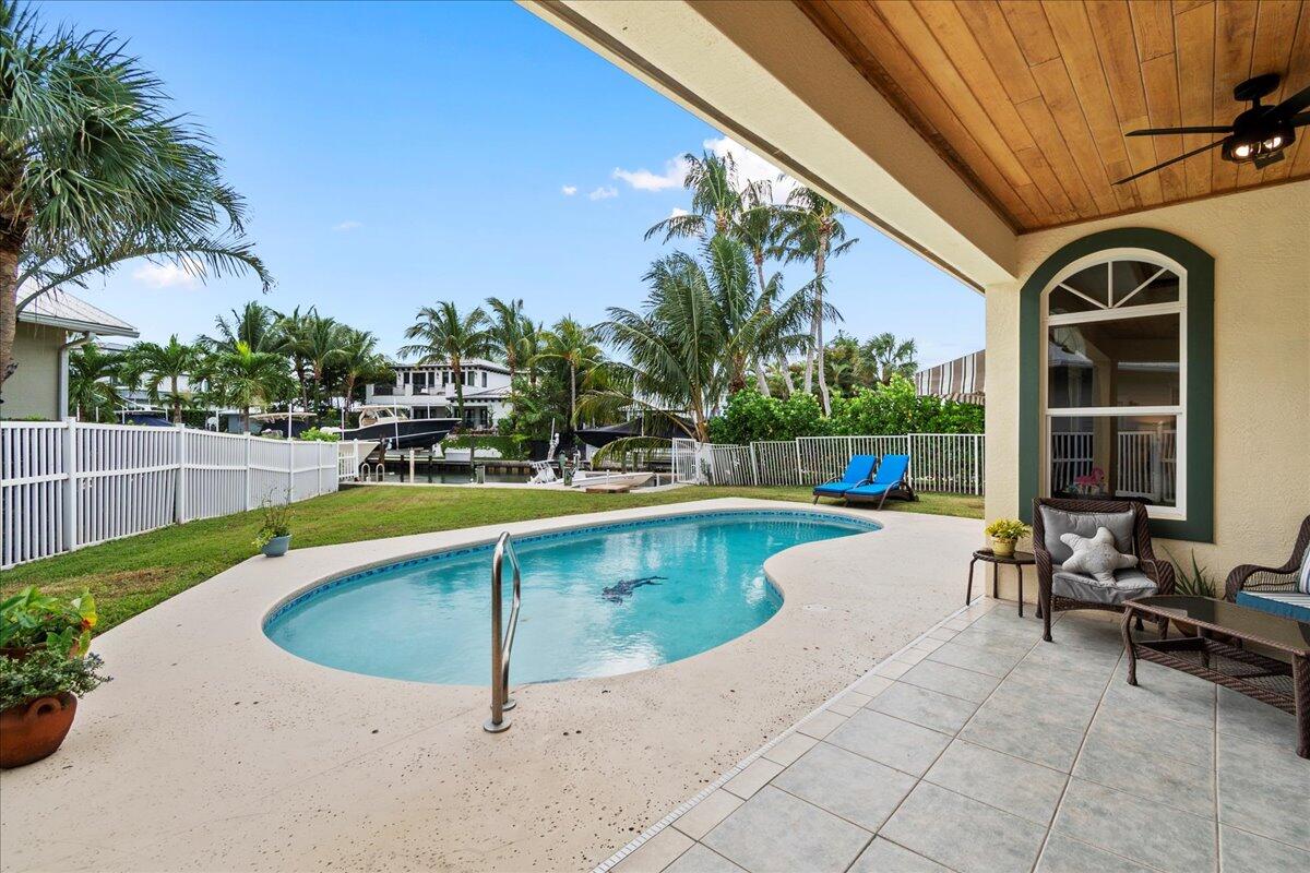 72 Waterway Road Jupiter, FL 33469 - Photo 30 of 57 a view of a swimming pool with a lounge chair and palm trees