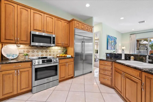 a kitchen with stainless steel appliances granite countertop a stove a sink and a refrigerator