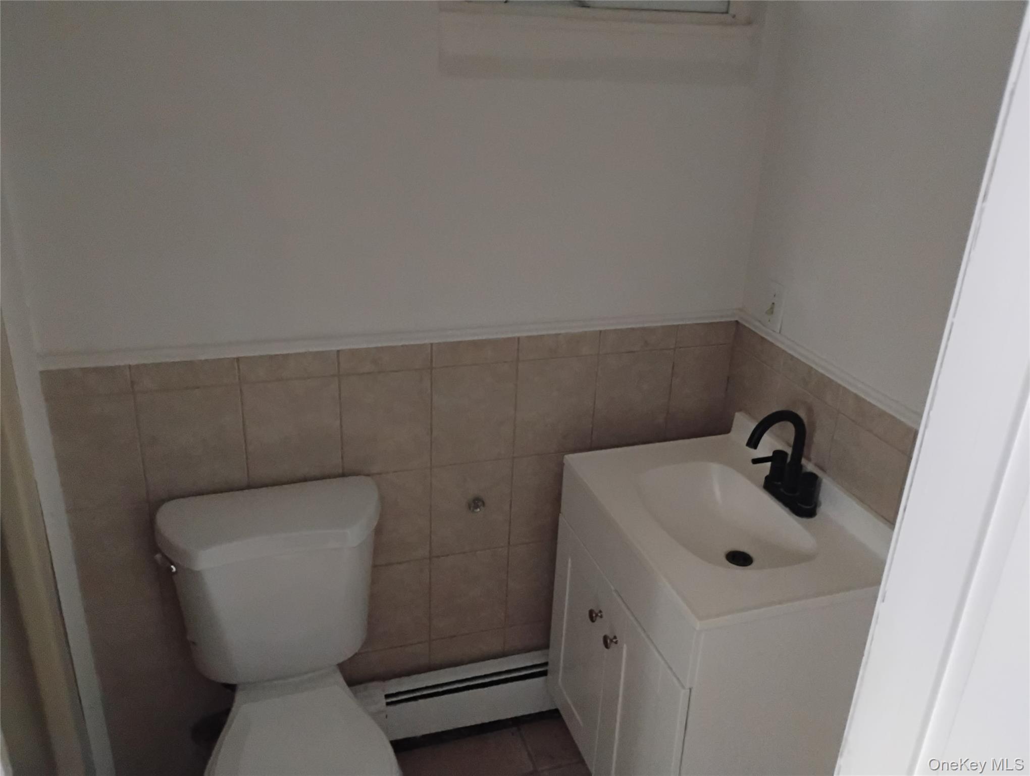 9 Merriewold Lane South Monroe, NY 10950 - Photo 11 of 14 Bathroom featuring vanity, a baseboard heating unit, tile walls, a wainscoted wall, and tile patterned flooring