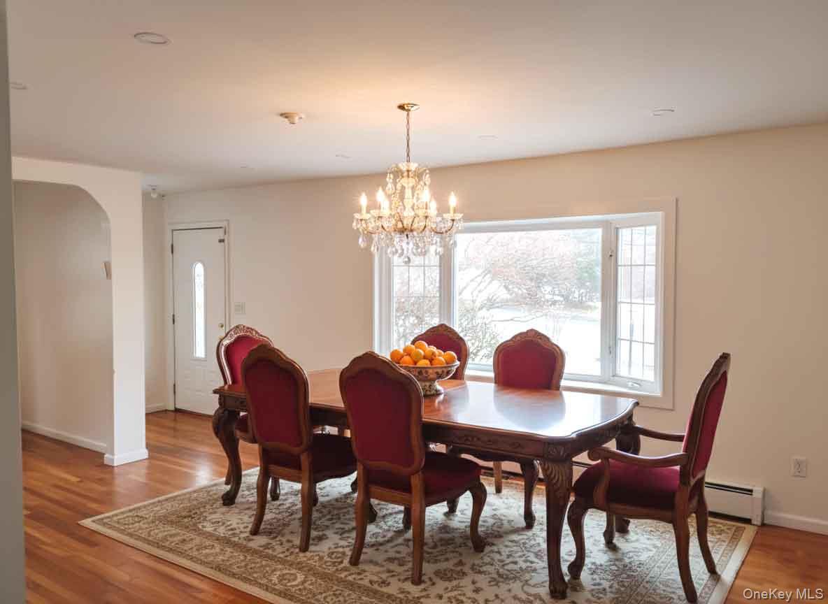 9 Merriewold Lane South Monroe, NY 10950 - Photo 6 of 14 Dining room with light wood-style flooring, a chandelier, a baseboard radiator, and arched walkways
