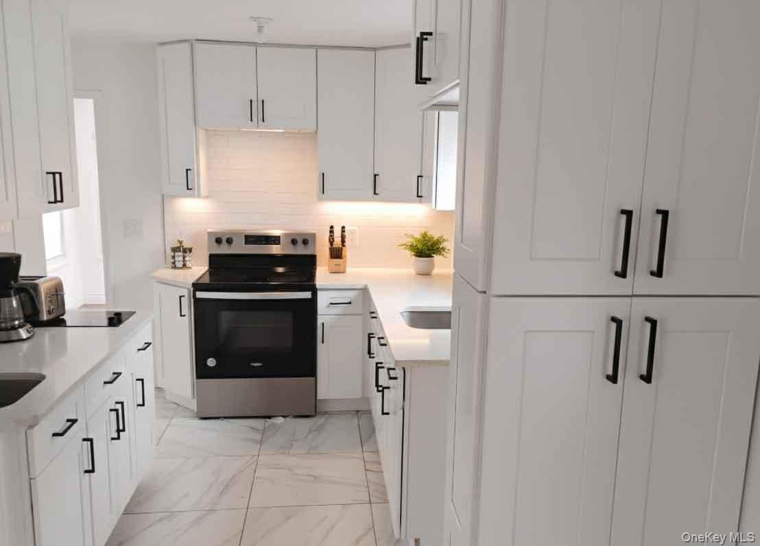 9 Merriewold Lane South Monroe, NY 10950 - Photo 7 of 14 Kitchen with stainless steel range with electric cooktop, white cabinets, light marble finish flooring, light stone counters, and tasteful backsplash