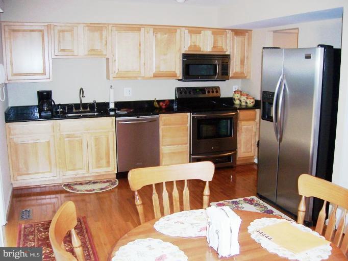 2936 Jermantown Road, Unit 10 Oakton, VA 22124 - Photo 2 of 7 a kitchen with stainless steel appliances a refrigerator a stove a sink a dining table and chairs