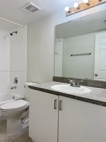 a bathroom with a granite countertop sink a toilet and a mirror
