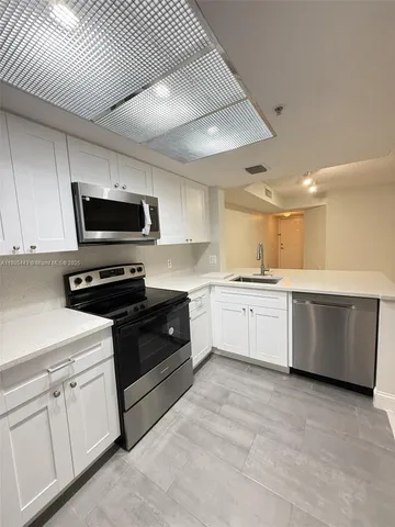a kitchen with a white stove top oven a sink and dishwasher with white cabinets
