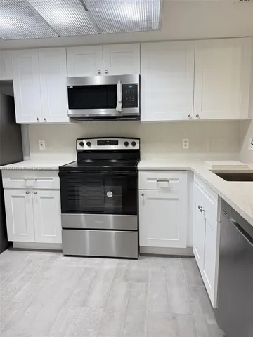a kitchen with white cabinets and stainless steel appliances