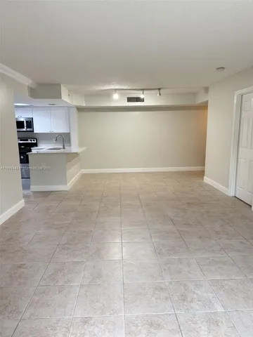 a view of kitchen and empty room with cabinet