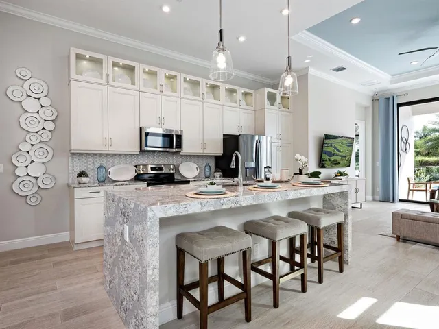 a kitchen with stainless steel appliances granite countertop a stove a sink a microwave a dining table and chairs with wooden floor