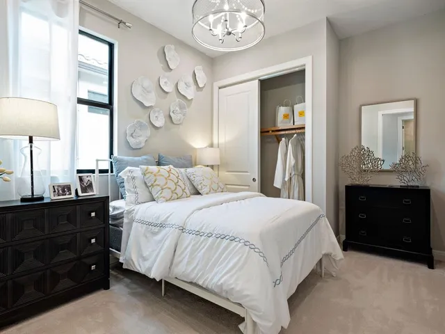 a bedroom with a bed and a lamp on dresser