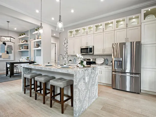 a kitchen with stainless steel appliances granite countertop a refrigerator a stove a sink a dining table and chairs