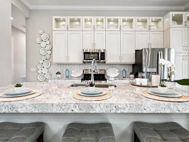 a kitchen with granite countertop white cabinets and stainless steel appliances