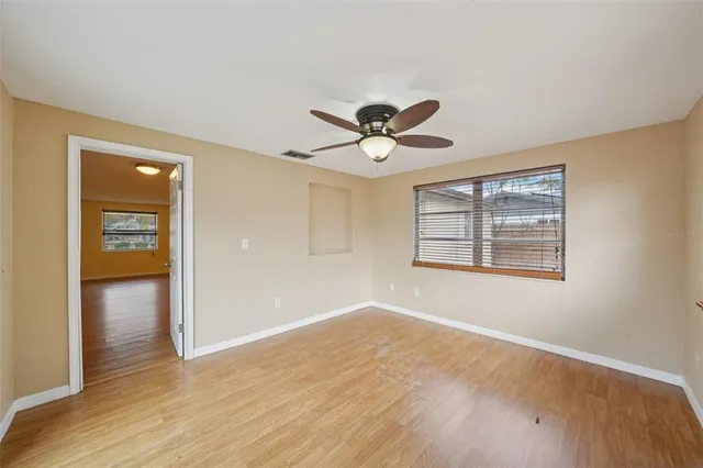a view of an empty room with a window and wooden floor