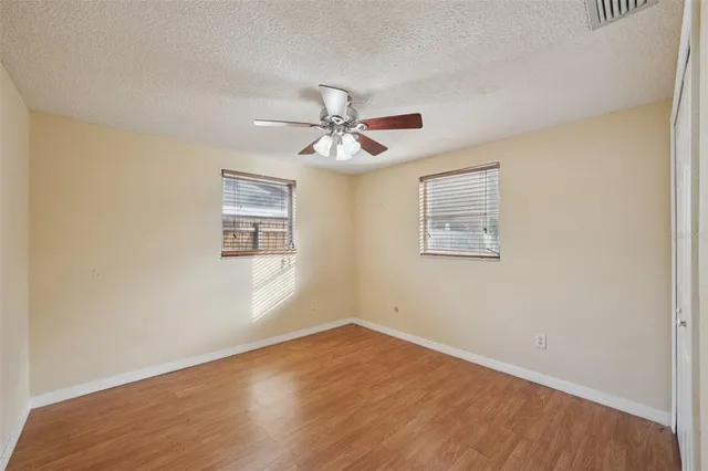 a view of an empty room with window and a ceiling fan