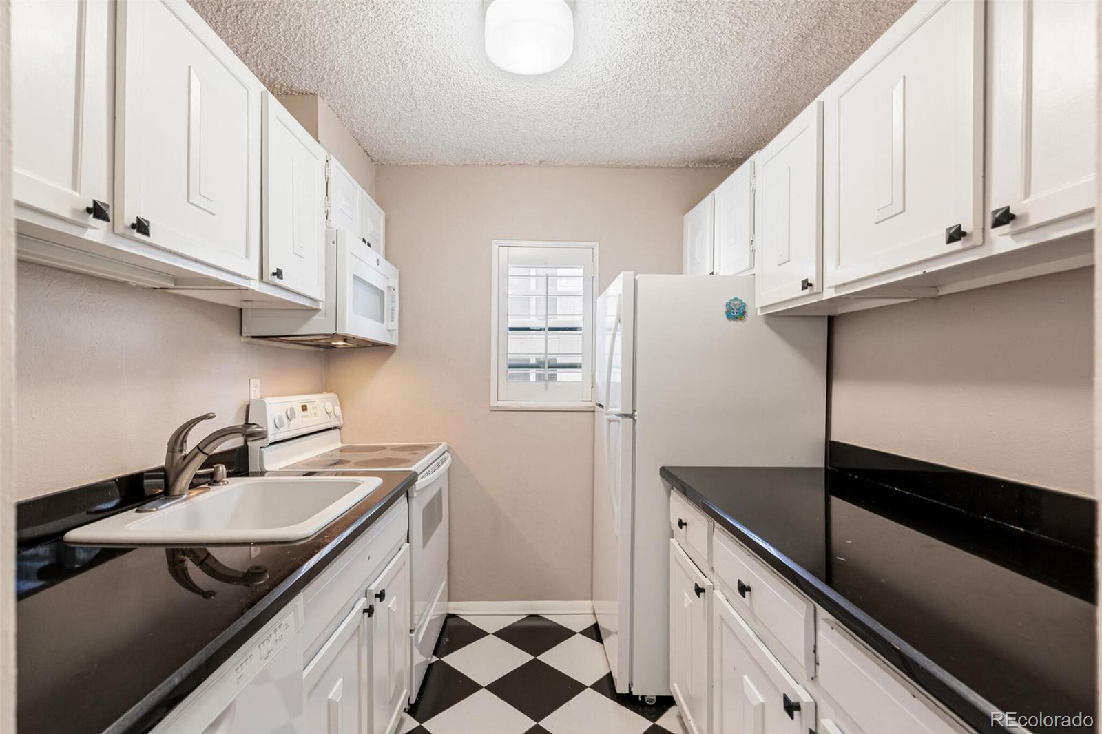 2 Adams Street, Unit 910 Denver, CO 80206 - Photo 7 of 15 a kitchen with stainless steel appliances granite countertop a sink and a refrigerator
