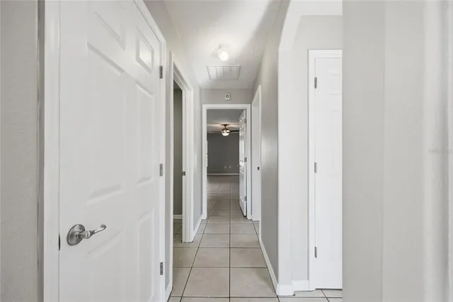 a view of an empty room with window and chandelier fan