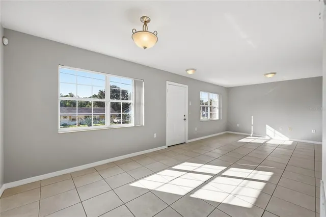 a view of an empty room with window and chandelier fan