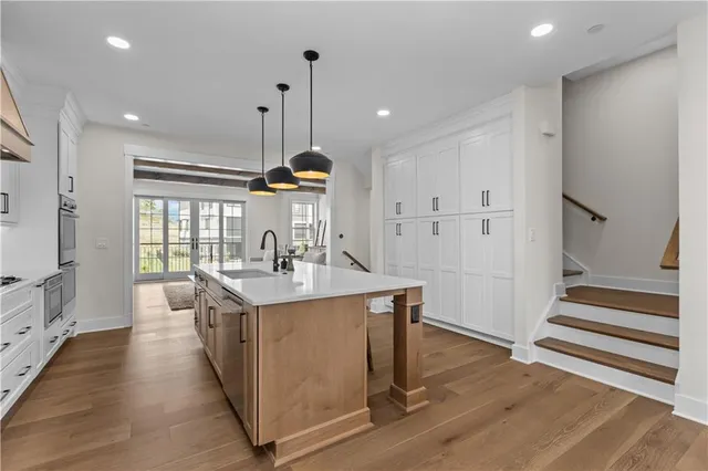 a kitchen with stainless steel appliances a stove a sink a refrigerator and wooden floor