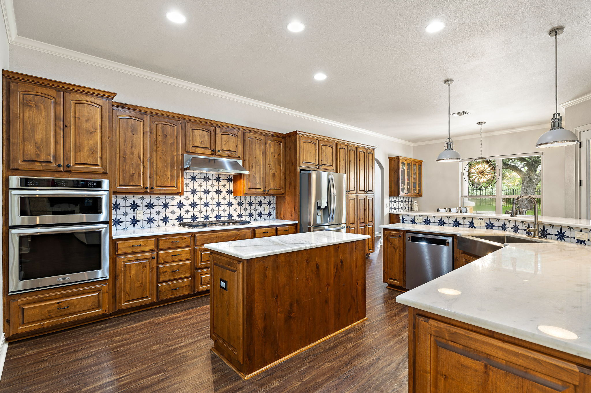 231 Marbella Way Georgetown, TX 78633 - Photo 7 of 40 Culinary aspirations meet elegant design in this kitchen, boasting custom cabinetry, white marble countertops, and vibrant tiled backsplash.